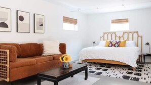 Ein modernes Schlafzimmer mit einem braunen Sofa, einem hölzernen Bett mit weißem Kopfteil und einem schwarz-weißen Teppich.