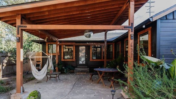 A covered patio with a hammock, outdoor seating, and a wooden pergola. - | The Jungle Bungalow | Downtown Chico | (Chico)