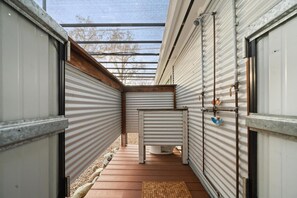 A narrow corridor with metal shutters, a wooden deck, and a small white structure in the center. - Visit our bright, spacious and clean centrally located one bedroom! (Chico)