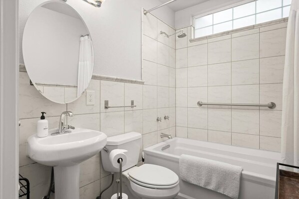 A modern bathroom with a sink, toilet, bathtub, and shower.