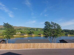 A lakeside view with wooden cabins and a clear sky.