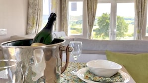 Et værelse med et bord dækket til et måltid, en champagneflaske og udsigt til det fri.
