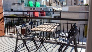 A balcony with a wooden table and chairs, overlooking a cityscape with buildings and balconies. - Veranda Apt close to Monastiraki - 1 (Athens)