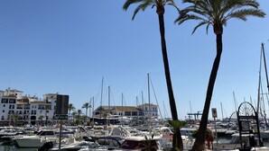A marina with boats docked, palm trees, and a building with a sign reading "PANTALAN". - Beautiful modern apartment 1 min from beach (Marina de Casares)