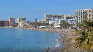 A beach with people, a clear sky, and buildings in the background. - Beautiful modern apartment 1 min from beach (Marina de Casares)