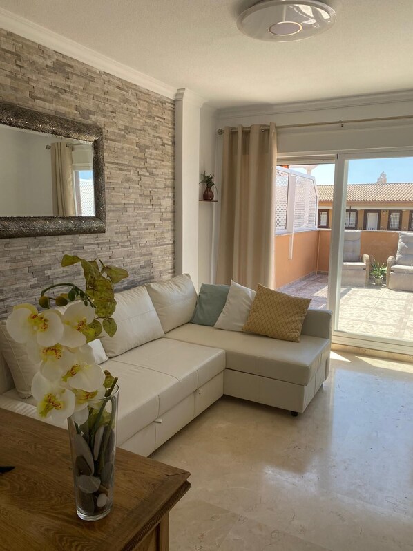 A modern living room with a sectional sofa, a decorative mirror, and a view of the outside.