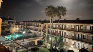 A multi-story hotel with a swimming pool, palm trees, and a full moon in the background. - Beautiful modern apartment 1 min from beach (Marina de Casares)