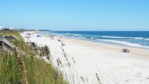 Une plage avec une promenade en bois, des tentes et des gens qui se détendent.