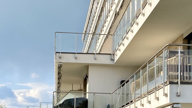 A modern multi-story building with a glass facade, a flat roof, and a landscaped garden. - Sunset Beach Apartment directly on the beach high-quality furnishings pool garden WLAN (Siófok)