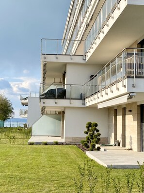 A modern multi-story building with a glass facade, a flat roof, and a landscaped garden. - Sunset Beach Apartment right on the beach, high-quality furnishings, pool, garden, Wi-Fi (Siófok)
