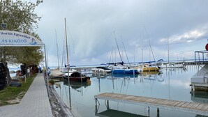 A marina with boats docked, a wooden dock, and a paved walkway. - Sunset Beach Apartment directly on the beach high-quality furnishings pool garden WLAN (Siófok)