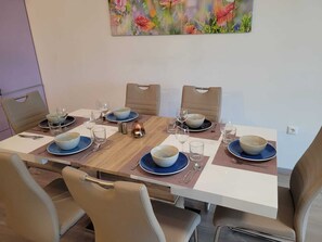 A dining table set for six with blue plates and white bowls, surrounded by beige chairs.