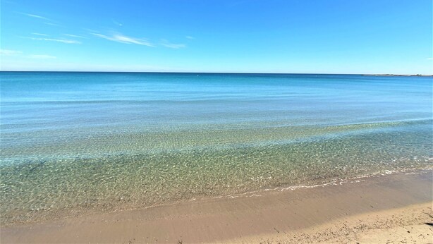 Vista despejada de una playa con aguas tranquilas y un cielo claro.