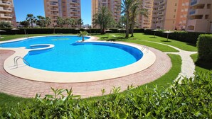 Una piscina de diseño circular, rodeada por un sendero de ladrillo y abundante vegetación.