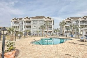 Relax by the central pool surrounded by palm trees and lounge chairs.