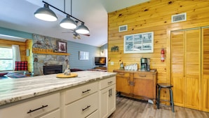 A kitchen with a stone fireplace, wooden walls, and a marble countertop. - Cozy Creekside Cabin w/ Fire Pit & Views! (Hayesville)