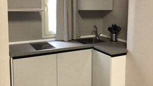 A modern kitchen with a built-in sink, a window with curtains, and a cabinet above the counter. - Dante 3 Guesthouse (Bari)