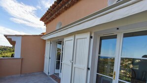 Una zona exterior coberta amb sòl de formigó, portes blanques i finestres grans.