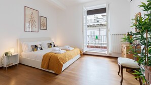 Ein Schlafzimmer mit Bett, Nachttisch und Fenster mit Blick nach draußen.