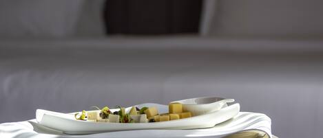 A neatly arranged breakfast buffet with various cheeses and garnishes on a white plate, set on a table with a white tablecloth.