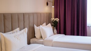 A hotel room with two beds, a headboard, a vase with flowers, and a wall-mounted lamp. - Orient Hotel Bishkek (Bishkek)