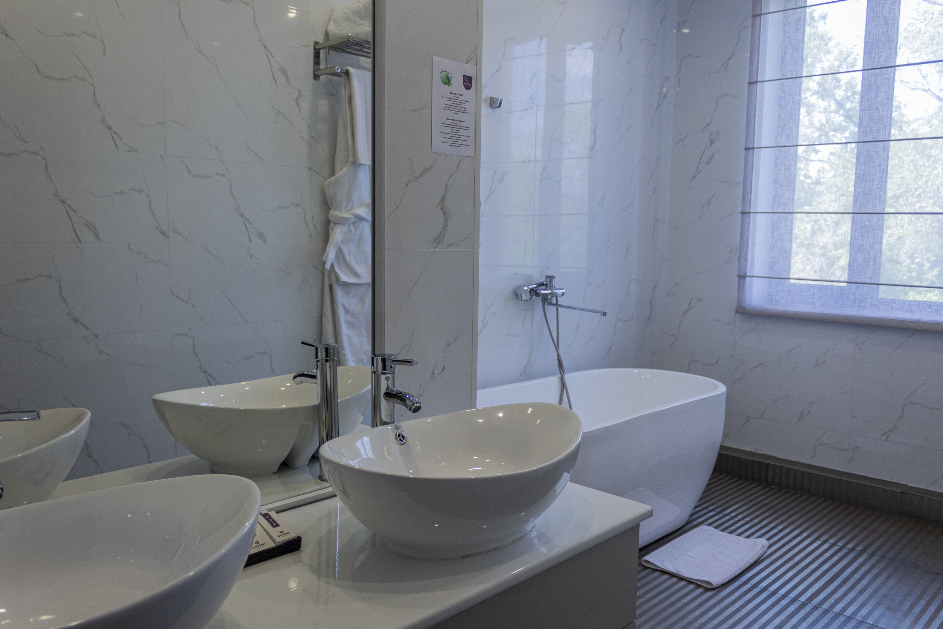 A modern bathroom with two large white sinks, a freestanding bathtub, and a shower.