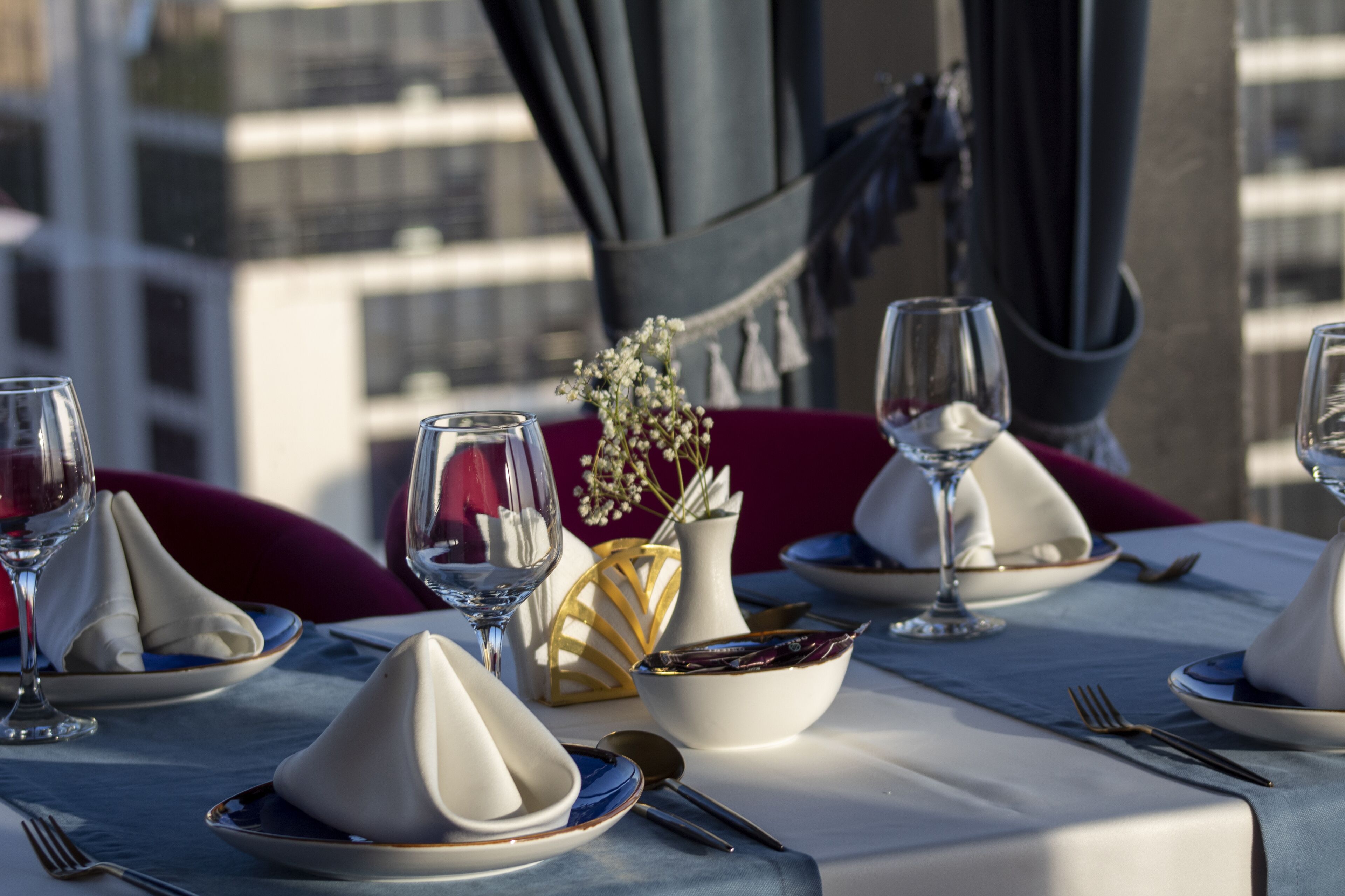 Une table mise pour un repas, avec des serviettes blanches, un bol et des verres à vin.