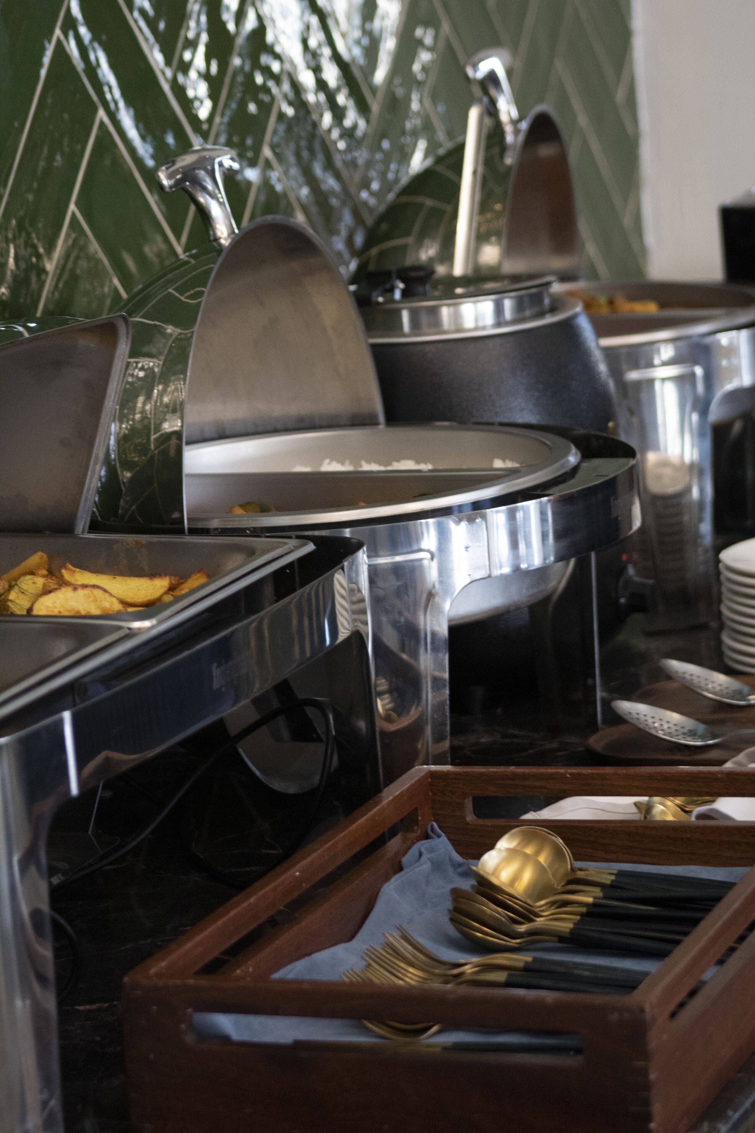 A buffet setup with various food containers and serving utensils.