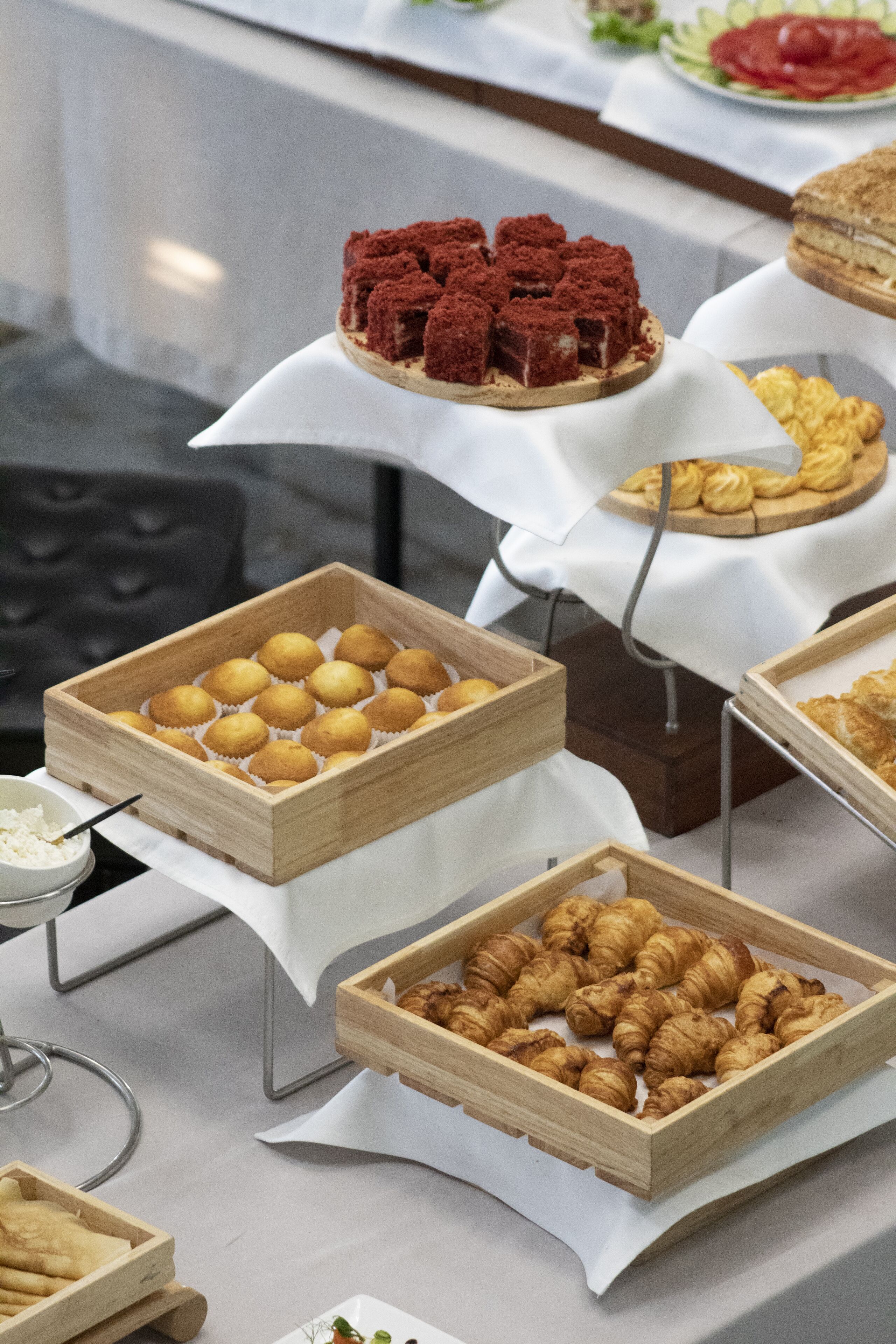Ein reichhaltiges Buffet mit verschiedenen Speisen, darunter Gebäck und Desserts in Holzeinlagen.