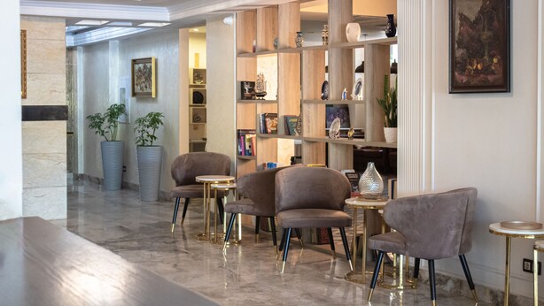 A lobby with marble flooring, a bookshelf, and seating areas. - Orient Hotel Bishkek (Bishkek)