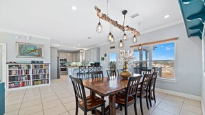 A spacious kitchen with a large island, a dining area with a wooden table and chairs, and a view of the beach through large windows. - Gorgeous 3 Bd/ 2+Ba home w/unobstructed views & easy beach access (Gulf Shores)