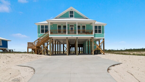 A two-story beach house with a balcony, wooden deck, and a concrete pathway leading to the entrance. - Elevator & Private Pool- Luxury 6 Bd, 6 Ba Home. Close to Beach w/amazing views (Gulf Shores)