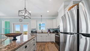 A modern kitchen with white cabinets, a stainless steel refrigerator, and a granite countertop. - Elevator & Private Pool- Luxury 6 Bd, 6 Ba Home. Close to Beach w/amazing views (Gulf Shores)