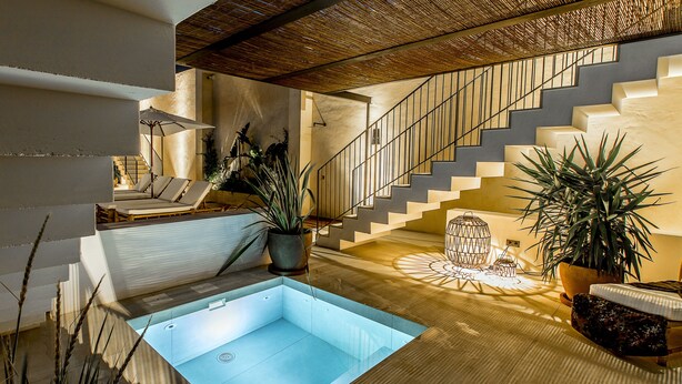 Un interior moderno con piscina, escalera y sillones de descanso.