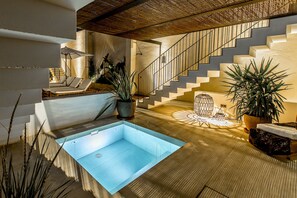 Un intérieur moderne avec une piscine, un escalier et des chaises longues.