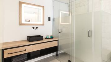 Een moderne badkamer met een houten wastafelmeubel, een douchecabine van glas en een spiegel met houten lijst.