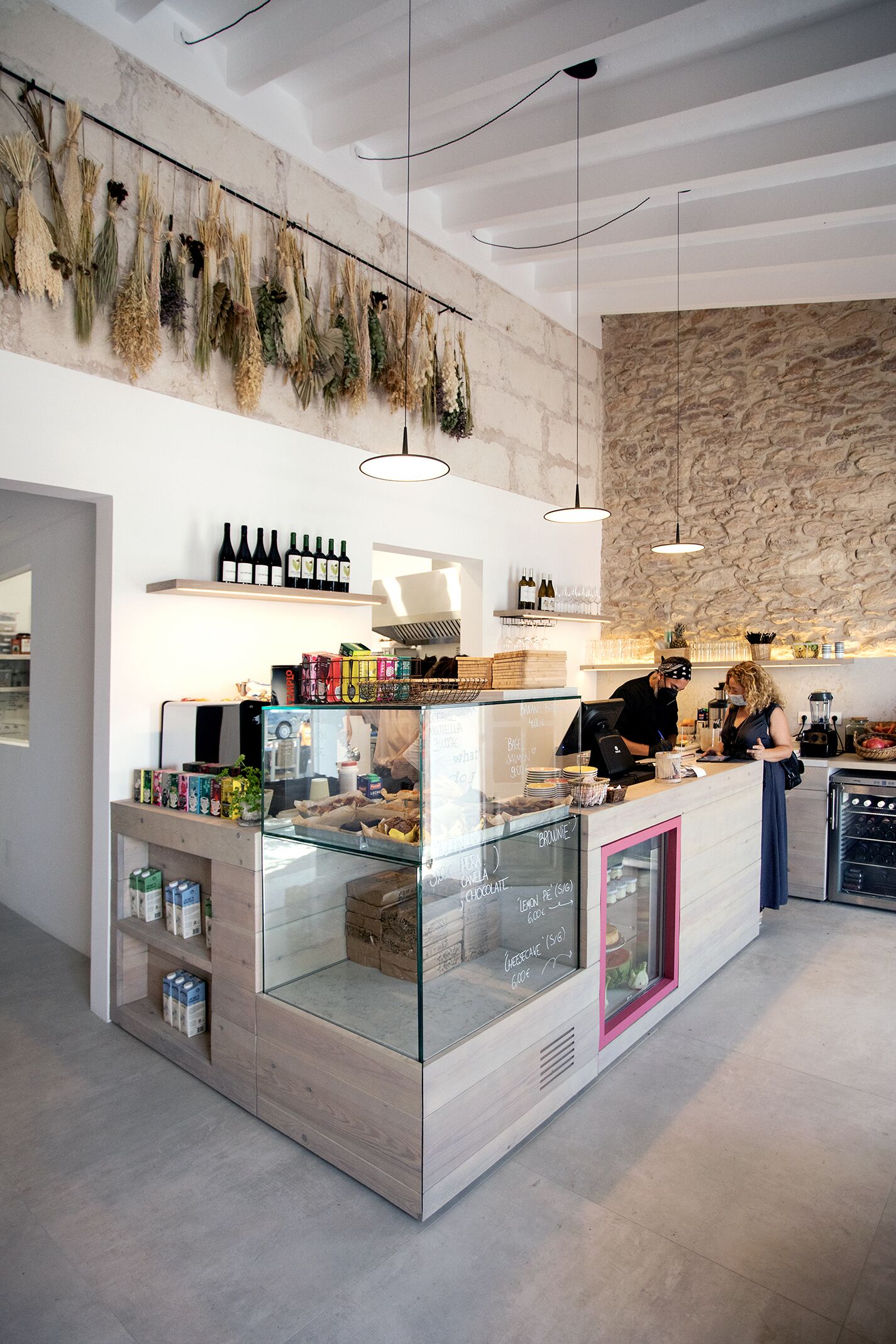 Un bar moderno con pared de piedra, estantes de madera y plantas colgantes.