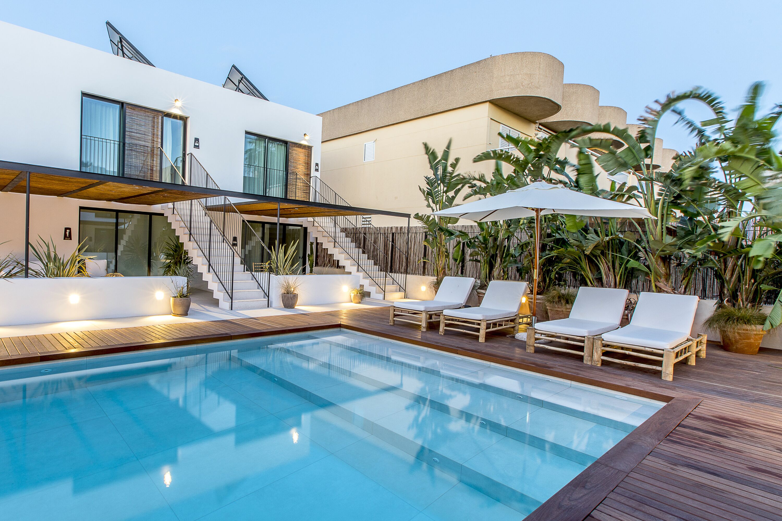 A modern pool area with a clear pool, wooden deck, and lounge chairs.