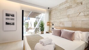 Una habitación de hotel moderna con una cama grande, cabecera de madera y vistas al exterior.
