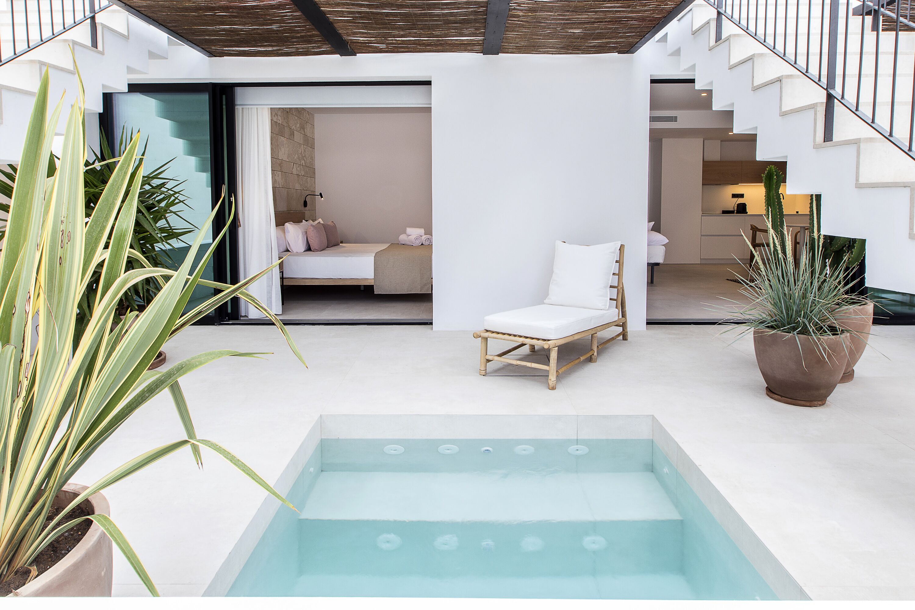 Un espace piscine extérieur moderne, avec un fauteuil en bois et un bain à remous.