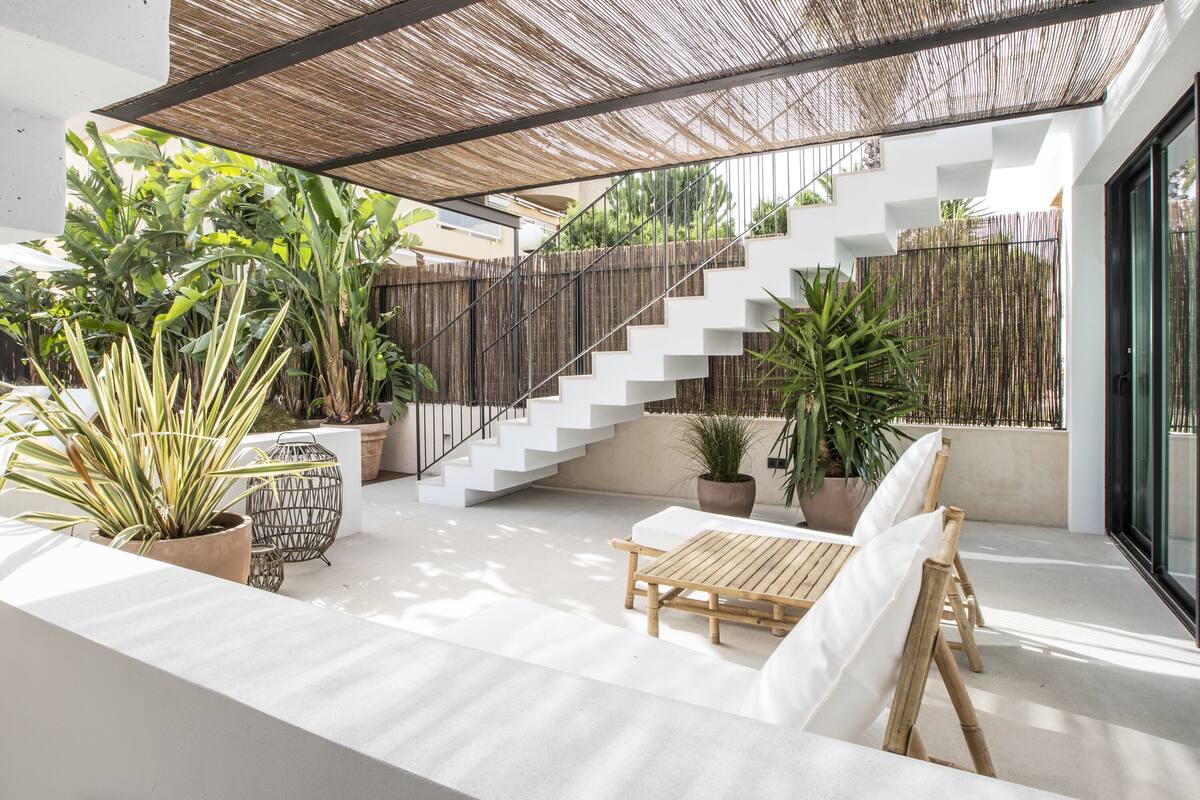 A modern outdoor patio with a staircase, potted plants, and a wooden table.