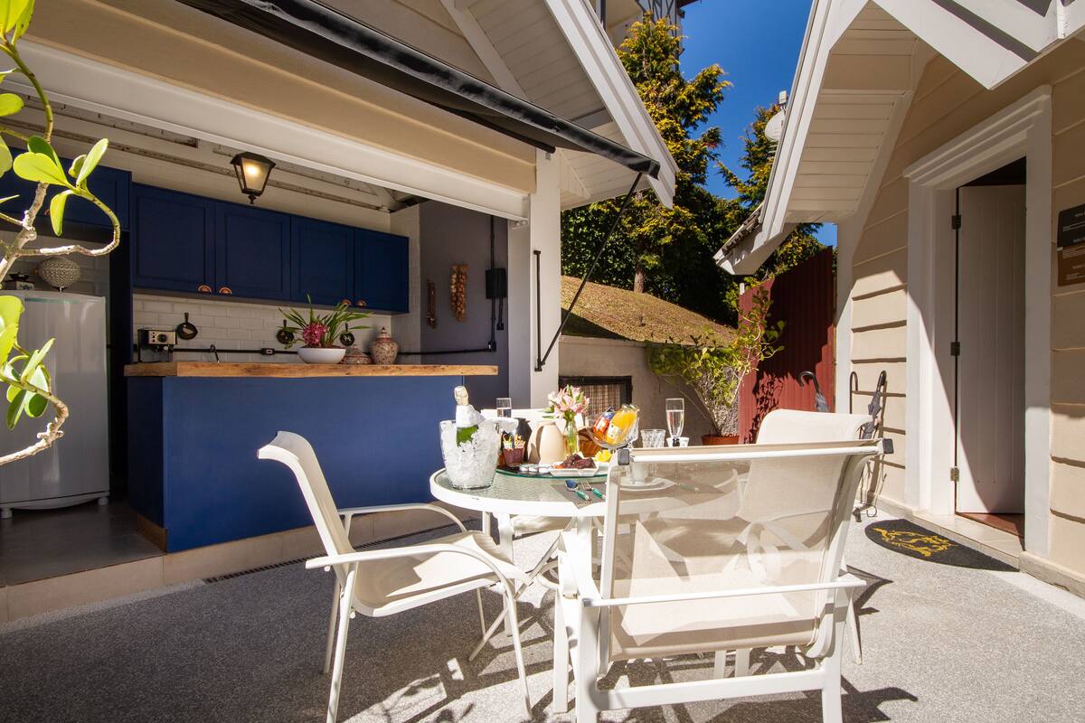 A patio with a table and chairs, a blue kitchen area, and a door leading to the interior.