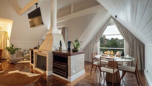 Amplia sala de estar con chimenea, una mesa de comedor y un ventanal con vistas al exterior.