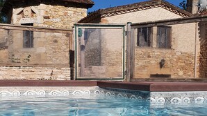 A swimming pool with clear blue water, surrounded by stone buildings with tiled roofs. - Domaine du Cardou (Puy-l'Eveque)
