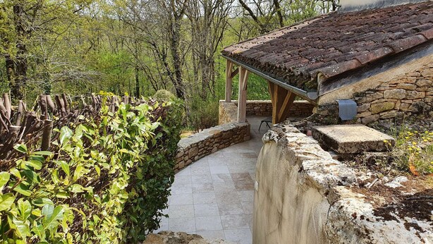 A rustic stone pathway leading to a wooden pergola with a tiled roof. - Domaine du Cardou (Puy-l'Eveque)