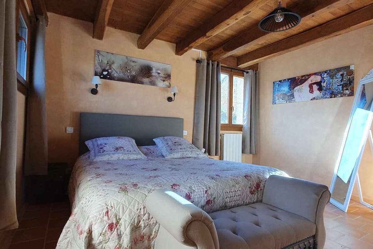 A bedroom with a bed, a chair, and two paintings on the walls.