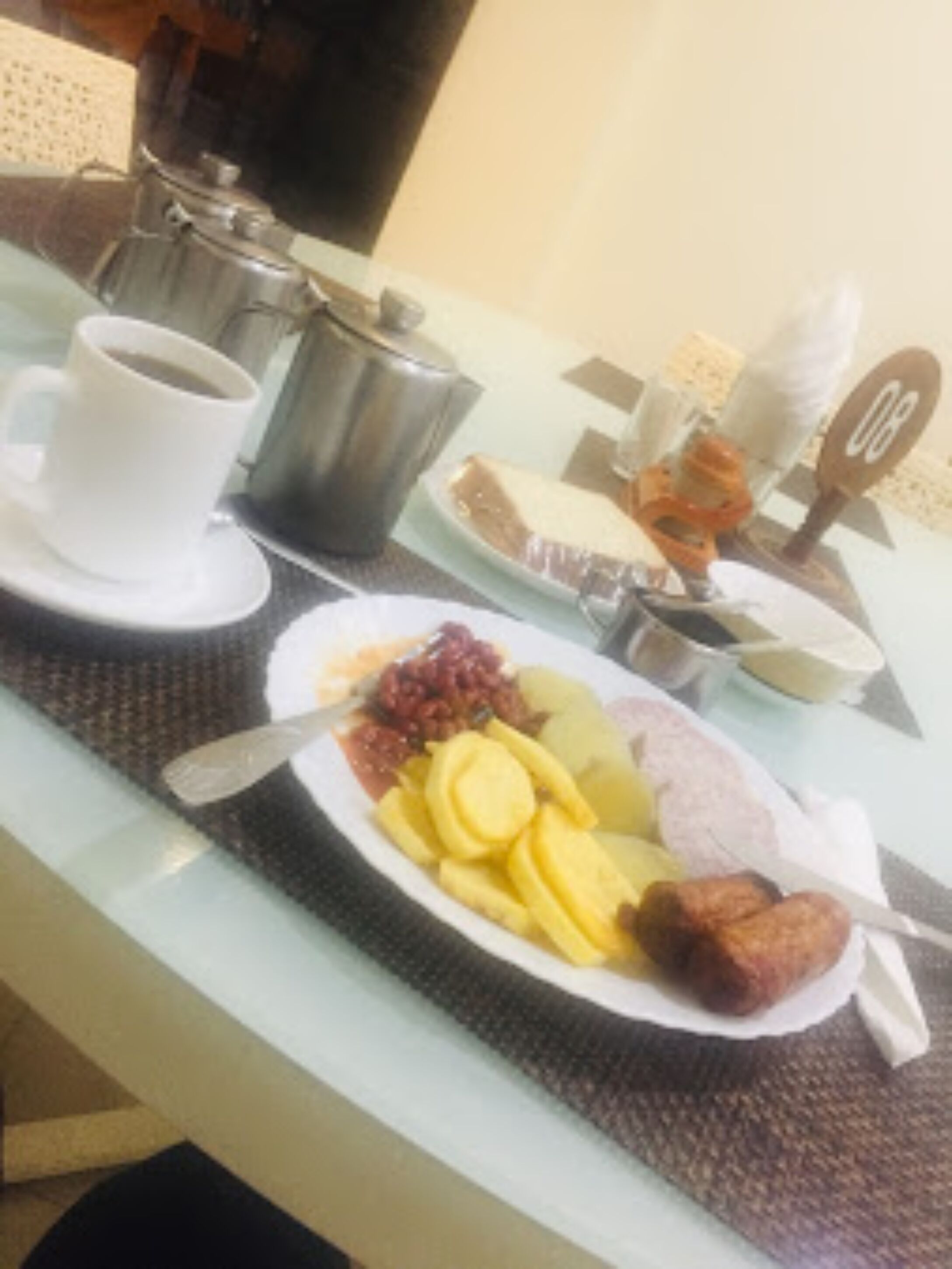 Una mesa de desayuno con un plato de comida, una taza de café y una tetera.