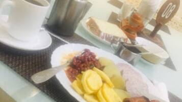 Una mesa de desayuno con un plato de comida, una taza de café y una tetera.