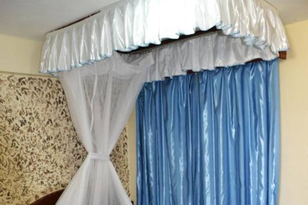 A bed with a canopy, striped bedding, and a headboard against a patterned wall.