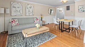 A living room with a grey sofa, a wooden coffee table, and a patterned rug. - Asbury: Work Friendly & 40 Mins to DC (Sterling)